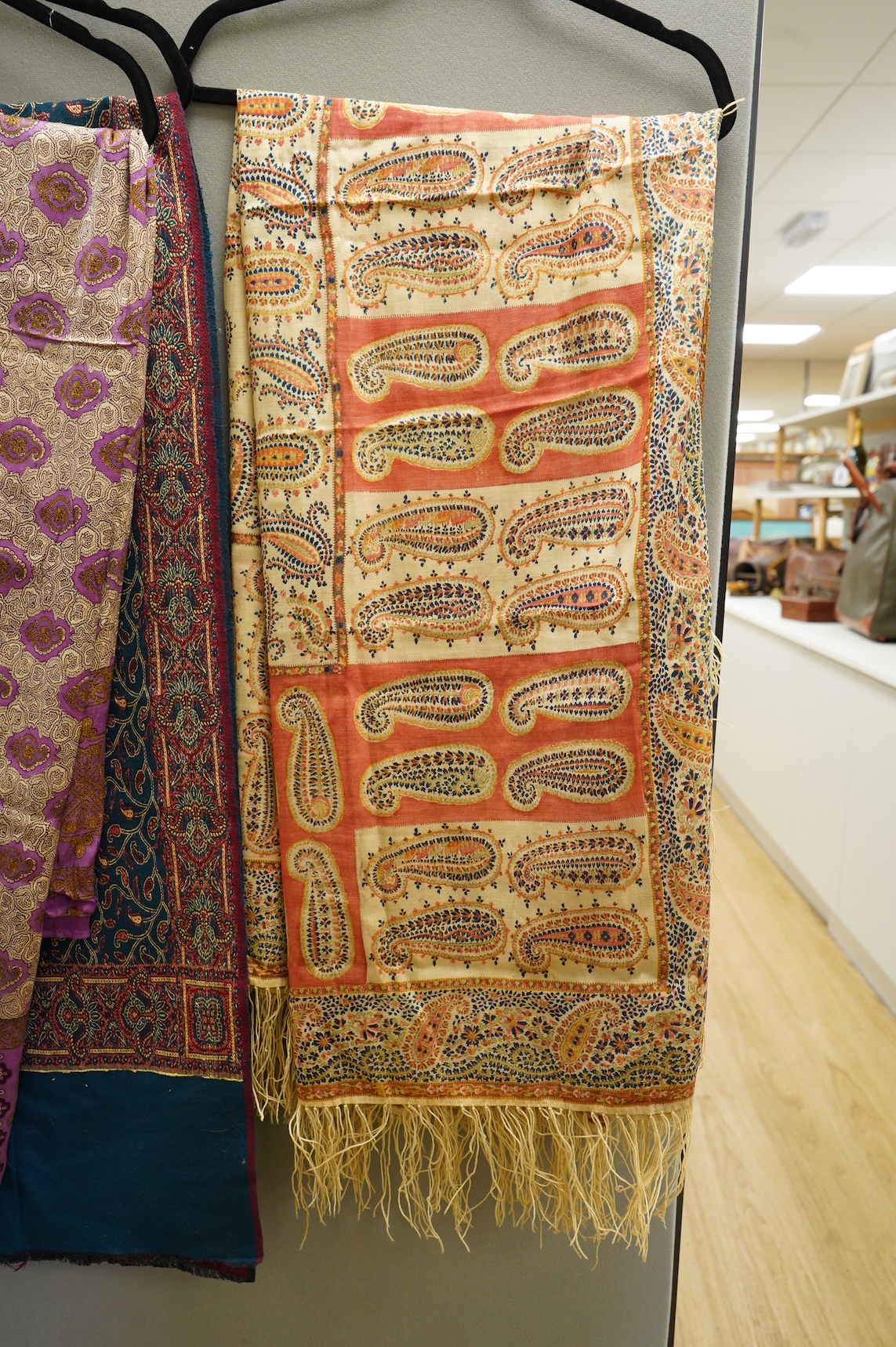 A 19th century printed silk shawl and a printed paisley shawl, together with a late 20th century wool machine woven stole with Oswal label. Condition - the two 19th century shawls are damaged but useful for TV and film c